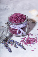 Obraz na płótnie Canvas A jar of purple bath salt with lavender, towel and candles vertical photo