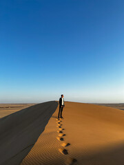 Young man walks along sandy dunes. Dune 17 in Namibia. 