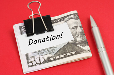On a red background lies a pen and dollars clamped with a clip with the inscription on paper -...