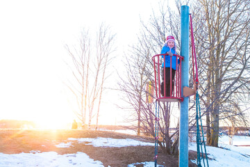The child, a little Caucasian girl plays on the playground. The child climbed onto the observation...