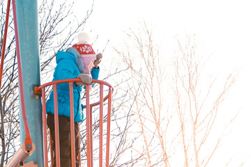 The child, a little Caucasian girl plays on the playground. The child climbed onto the observation...