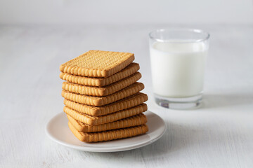 glass of milk and cookies.stacks of tasty cookies on the white plate. square biscuits on the white table with copy space. healthy eating