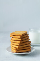 Fototapeta na wymiar cookies and milk.stacks of tasty cookies on the white plate. square biscuits on the white table with copy space. healthy eating. vertical