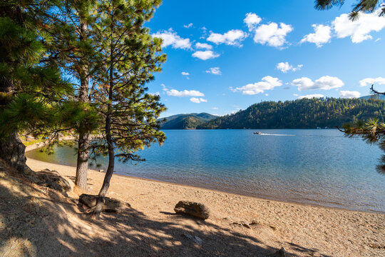 A boat passes in front of a small sandy beach at Beacon Point, a stop on the Centennial Trail, on lake Coeur d'Alene's Wolf Lodge Bay, in Coeur d'Alene, Idaho, USA.