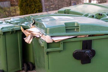 Overfilled green dustbin with open lid