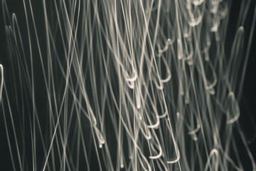 Abstract rays of sandy hue on a black background. Drawing with light. Chaos. Curved wave lines.