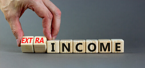 Extra income symbol. Businessman turns wooden cubes and changes concept words income to extra...