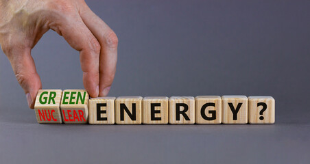 Nuclear or green energy symbol. Businessman turns wooden cubes and changes concept words nuclear energy to green energy. Beautiful grey background copy space. Business nuclear green energy concept.