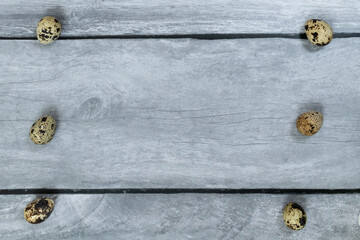 Easter background. Three quail eggs left and right against a light wood background.