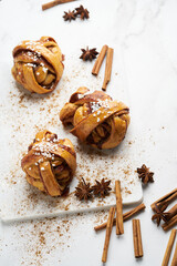 Fresh vegan cinnamon buns on marble board and white marble table