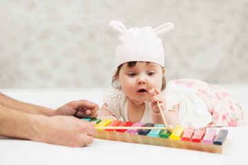 Half year baby girl playing with xylophone toy on blanket