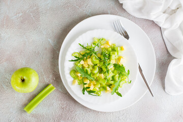 Dietary salad of celery, green apple, arugula and sesame seeds on plates on the table. Vegetarian food. Top view