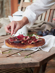 Obraz na płótnie Canvas hand delicately decorating a fig tart with fresh edible flowers