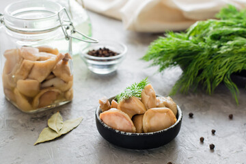 Pickled mushrooms - boletus in a bowl and in a glass jar on the table. Organic vegetarian food.