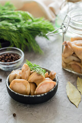 Delicious pickled mushrooms in a bowl and in a glass jar on the table. Vegetarian organic food. Close-up. Vertical view