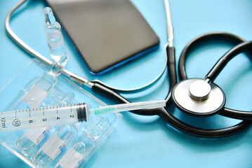 Medical background with syringe and glass ampoules, stethoscope.