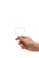 Hand holding a heart mold on a white background. Vertical photo. Symbol for Valentine’s Day and love.