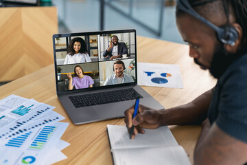 African American businessman using laptop for having virtual team meeting on video call with different people, work from home office or coworking, online meeting, briefing, brainstorming