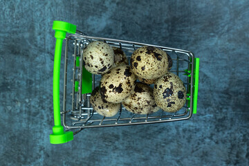 Easter background. Quail eggs in a cart on a dark background.