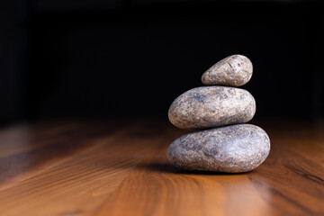 Obraz na płótnie Canvas Balancing 3 beige zen stones on wooden table