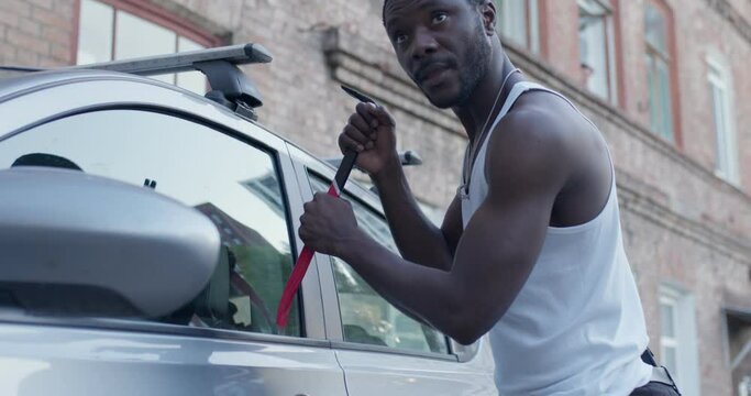 Black Car thief steal car breaking door criminal job burglar Hijacks Auto thief trying break into vehicle. Street crime violence gangster robber automobile parking. strong guy in white shirt at street