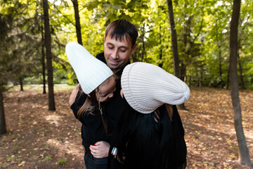 Parents hug their daughter. Woman and man and child in the park. Summer park. Green trees. The concept of a young family.