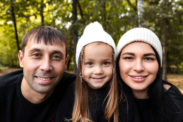 Mom, dad and little daughter. Close up of faces. Summer park. Green trees. The concept of a young family. Black and white photography.