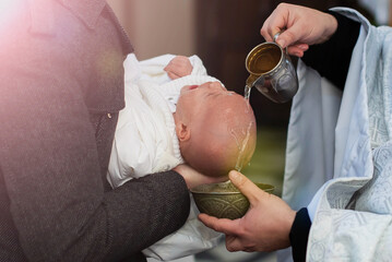 Infant baptism. Water is poured on the head of an infant. Baptism ceremony in Church.