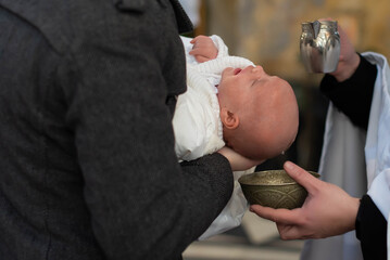 Infant baptism. Water is poured on the head of an infant. Baptism ceremony in Church.