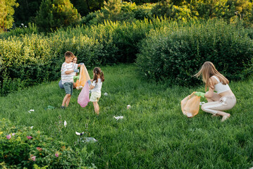 A group of adults and children together at sunset is engaged in garbage collection in the park....