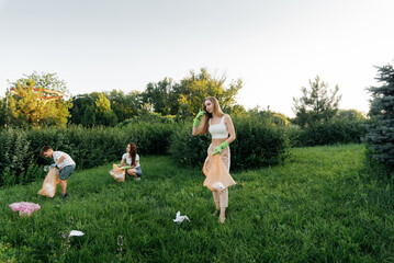 A group of adults and children together at sunset is engaged in garbage collection in the park. Environmental care, waste recycling. Sorting garbage.