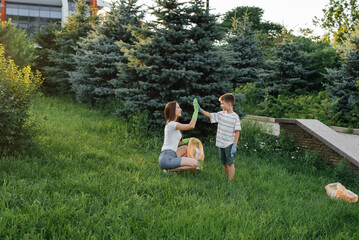 Mom and son are cleaning garbage in the park at sunset. Environmental care, waste recycling.