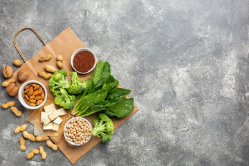 Concept: Purchase healthy clean food. Protein source for vegetarians: vegetables, nuts and legumes top view on a concrete background with a paper bag.