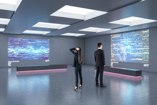 Businesspeople in abstract exhibition center looking at glowing polygonal NFT hologram. Technology, business and currency concept. - Powered by Adobe