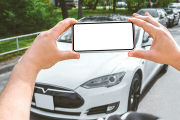 Smartphone mockup in the hands of a man. Against the background of a white electric car.