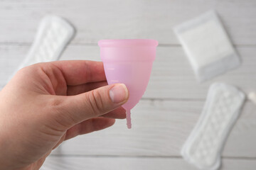 menstrual cup in hands. alternative feminine menstruation hygiene material product on wooden background 