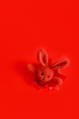 Red plush bunny easter bunny Climbs out peeking out of torn paper hole Isolated on red color background. Vintage baby easter bunny toy. Creative minimalist Concept Idea for design.