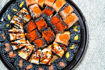 a set of rolls with black rice on a round plastic dish. cuttlefish ink. 