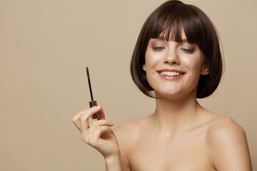 Obraz premium young woman paints eyelashes bare shoulders isolated background