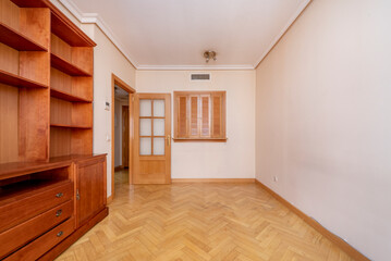 Living room with cherry colored wood furniture on one side and access window to the kitchen with Venetian wood doors