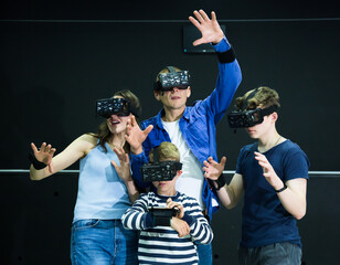 Emotional young parents with two teenage sons having fun with vr headset goggles. Concept of new technology and family entertainment..