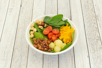 Spinach salad, cherry tomatoes, grated yellow pepper, diced ham, melon balls and peeled hazelnuts