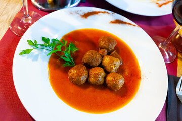 Pamplona cuisine meatballs and Navarra chistorra served with parley on plate on wooden table
