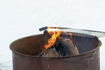 Camp fire in winter. snow surrounding metal campfire ring