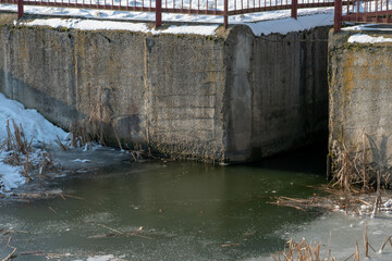 Irrigation canal along an agricultural field in winter covered with snow and ice. Winter landscape agrocomplex eco friendly. Wastewater treatment plants.