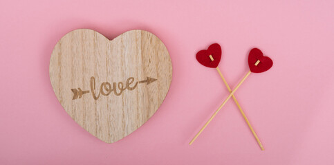 Wooden stand in the shape of a heart on a pink background