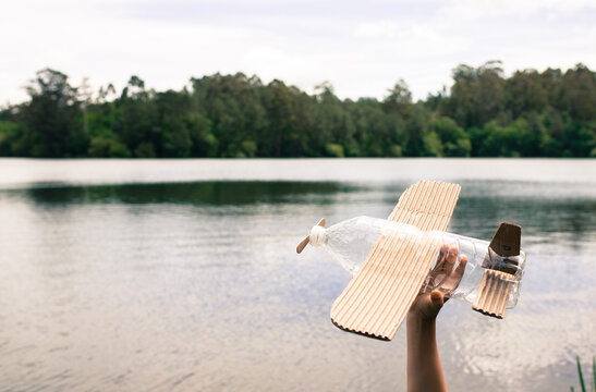 children's hands playing with a plane built with recycled material (wood, PVC bottles, cardboard)