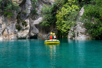 Fototapeta na wymiar tourists on an inflatable boat rafting down the blue water canyon in Goynuk, Turkey