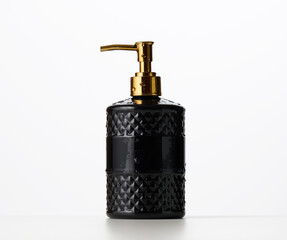 black plastic container with a golden dispenser on a white background. Container for liquid soap,...