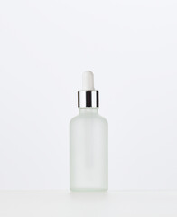 white glass bottle with a pipette on a white background. Template for cosmetic liquid products